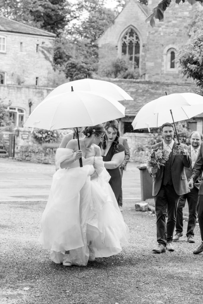 Black and white wedding photograph showing bride with umberella