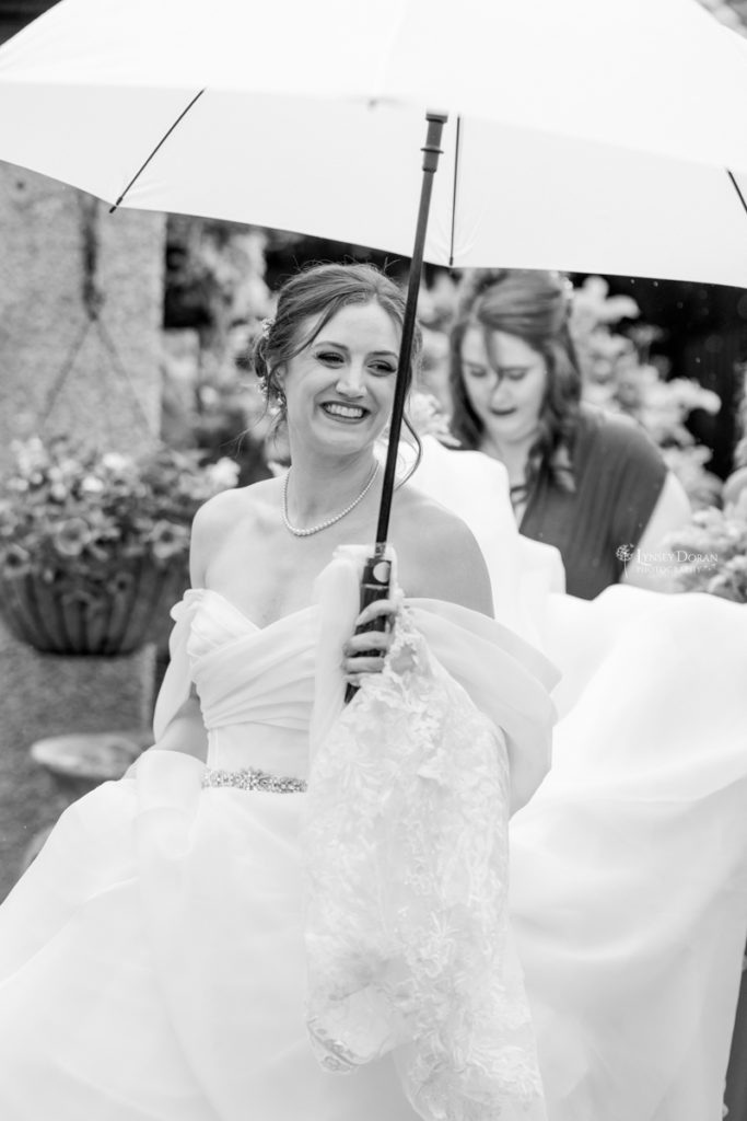 Black and white wedding photograph showing bride with umberella